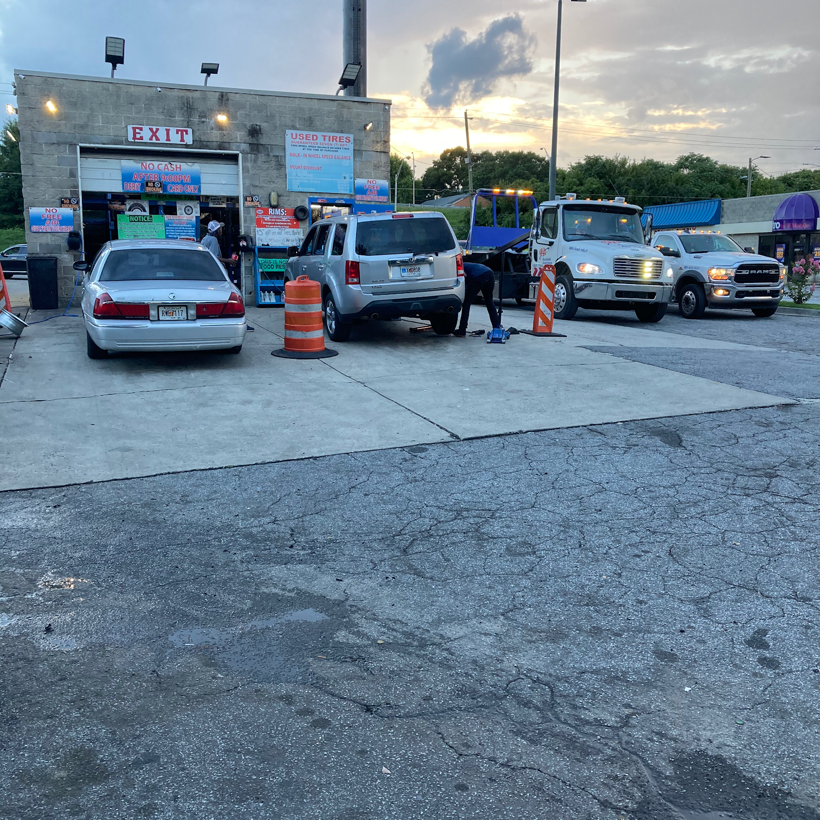 Tire & Ride Mobile — Atlanta shop yard with tow trucks and service vehicles at dusk, used-tires storefront sign visible